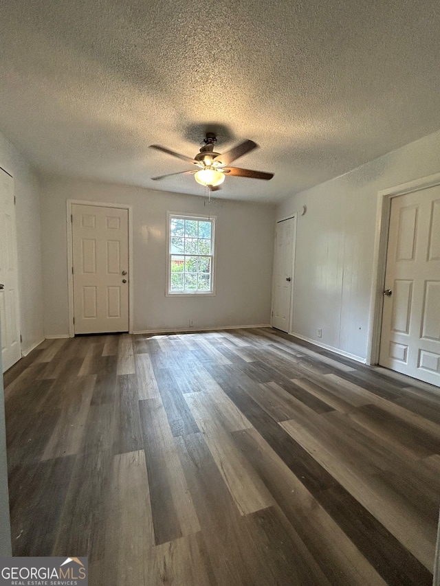 unfurnished room with a textured ceiling, dark hardwood / wood-style floors, and ceiling fan