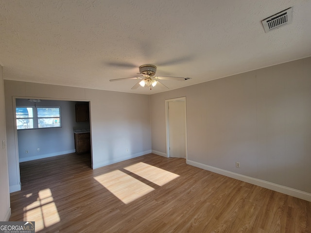 empty room with ceiling fan, a textured ceiling, and hardwood / wood-style floors