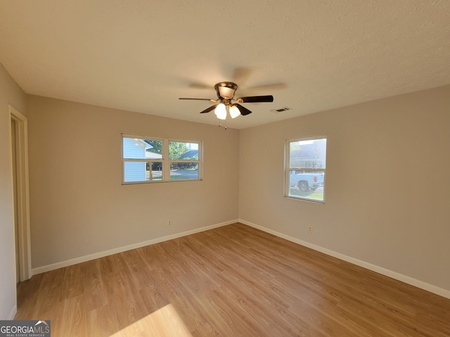 empty room featuring light hardwood / wood-style floors, ceiling fan, and a textured ceiling