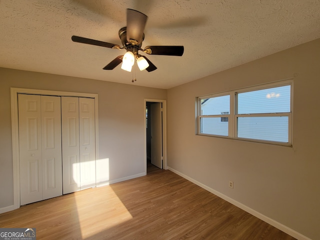 unfurnished bedroom featuring a textured ceiling, light hardwood / wood-style floors, ceiling fan, and a closet