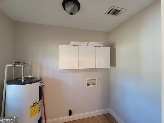 clothes washing area featuring light wood-type flooring, washer hookup, electric water heater, and cabinets