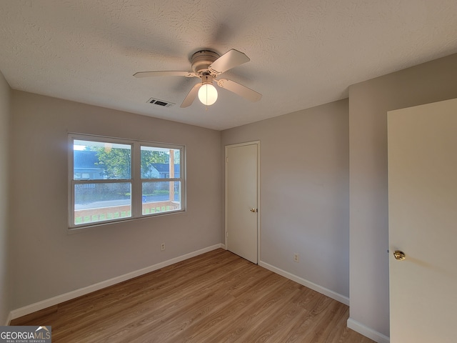 unfurnished room with ceiling fan, a textured ceiling, and light hardwood / wood-style floors