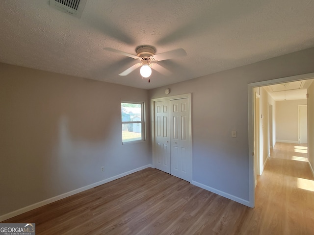 unfurnished bedroom featuring ceiling fan, light hardwood / wood-style flooring, and a closet