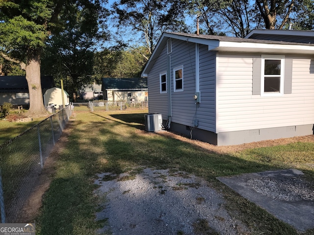 view of side of home featuring cooling unit and a yard