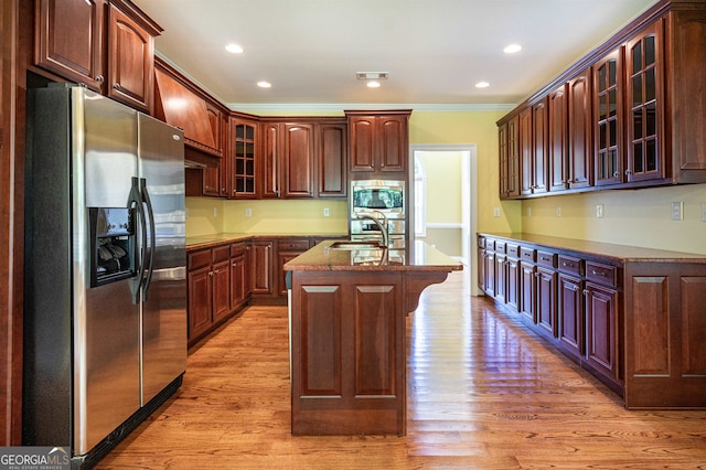 kitchen featuring light wood-type flooring, sink, a center island with sink, appliances with stainless steel finishes, and crown molding