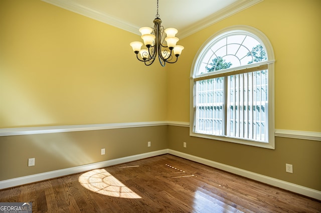 empty room with an inviting chandelier, dark hardwood / wood-style floors, ornamental molding, and a wealth of natural light