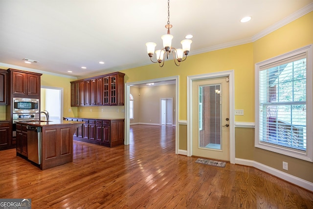 kitchen with a chandelier, a center island with sink, crown molding, and dark hardwood / wood-style flooring