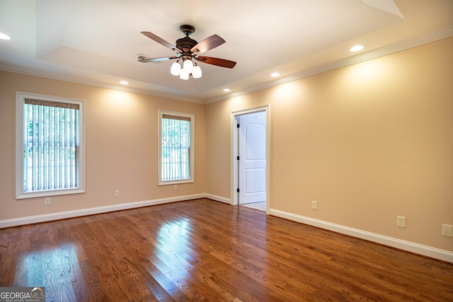 unfurnished room with ceiling fan, a raised ceiling, hardwood / wood-style floors, and crown molding