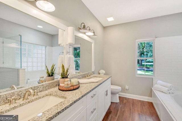 full bath featuring a garden tub, wood finished floors, a sink, and toilet