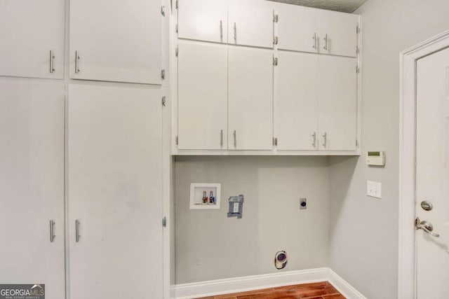 clothes washing area featuring hookup for an electric dryer, washer hookup, baseboards, cabinet space, and dark wood-style floors