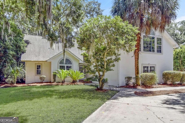 view of front of home featuring stucco siding, roof with shingles, concrete driveway, and a front yard