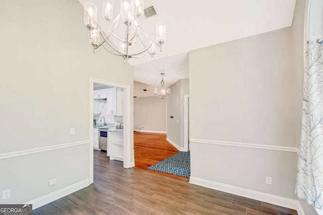 unfurnished dining area featuring wood finished floors, visible vents, baseboards, and an inviting chandelier