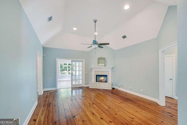 unfurnished living room featuring vaulted ceiling, a glass covered fireplace, visible vents, and light wood-style floors