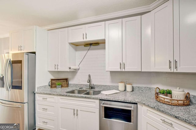 kitchen with stainless steel appliances, white cabinetry, a sink, and backsplash