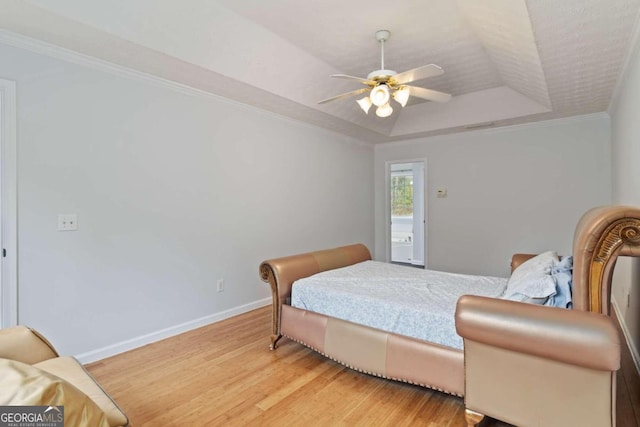 bedroom with a raised ceiling, crown molding, ceiling fan, and wood-type flooring