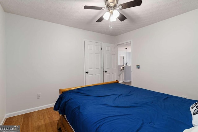 bedroom featuring ceiling fan, wood-type flooring, and a textured ceiling