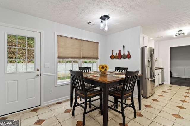 dining area with a textured ceiling, plenty of natural light, and light tile patterned flooring