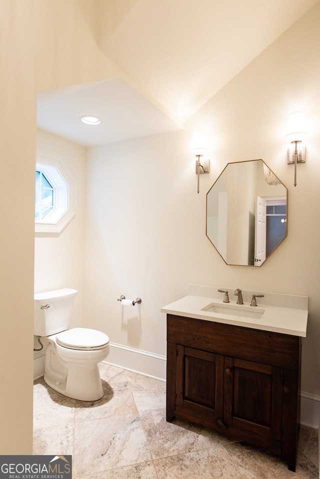 bathroom featuring vanity, toilet, and vaulted ceiling