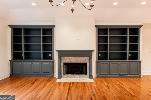 unfurnished living room featuring a fireplace, light hardwood / wood-style flooring, and a notable chandelier