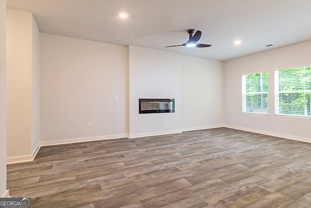 unfurnished living room featuring ceiling fan, heating unit, and hardwood / wood-style floors