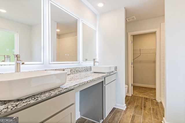 bathroom with walk in shower, vanity, hardwood / wood-style floors, and toilet