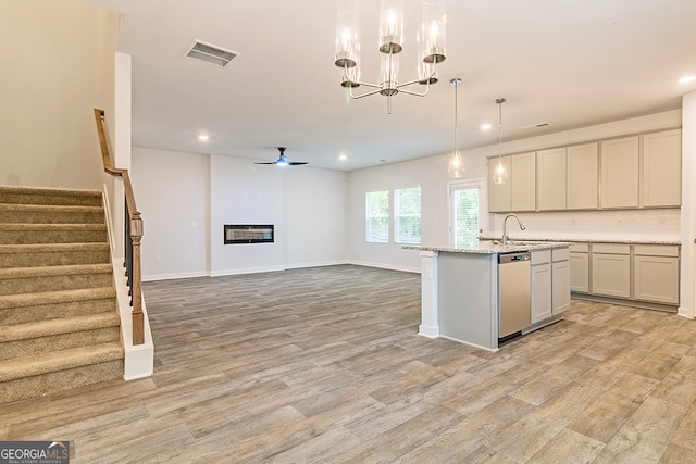 kitchen featuring pendant lighting, a kitchen island with sink, dishwasher, ceiling fan with notable chandelier, and light hardwood / wood-style floors