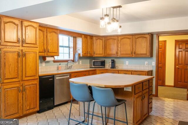 kitchen featuring appliances with stainless steel finishes, a center island, decorative light fixtures, wall chimney range hood, and a notable chandelier