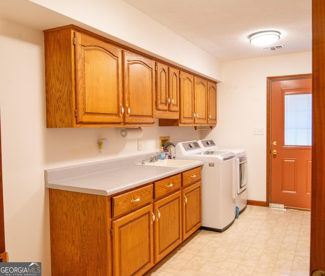 washroom featuring cabinets, washing machine and dryer, and sink