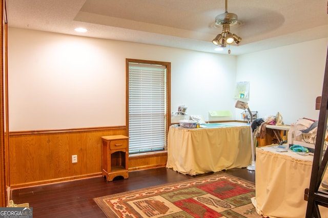 office area with ceiling fan, dark wood-type flooring, a textured ceiling, and wooden walls