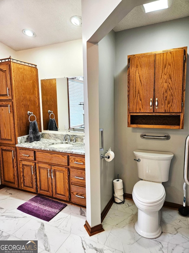 bathroom featuring a textured ceiling, toilet, and vanity