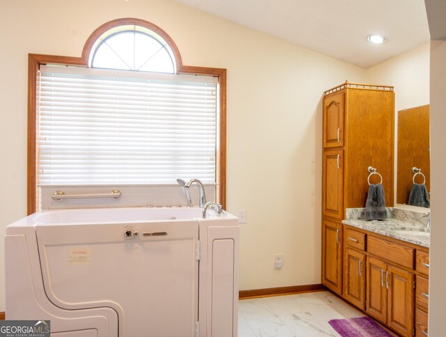 bathroom with walk in shower, vanity, and washer / dryer