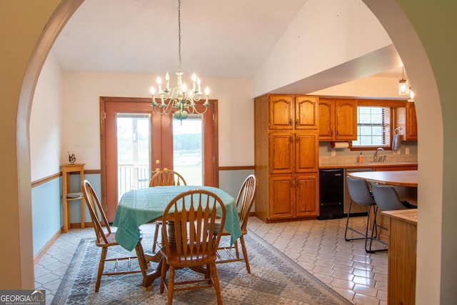 dining space with an inviting chandelier, vaulted ceiling, sink, and french doors