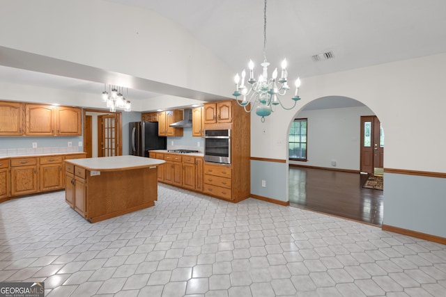 4909 Perry Rd, Claxton, GA 30417 - kitchen with appliances with stainless steel finishes, a chandelier, lofted ceiling, light countertops, and wall chimney range hood