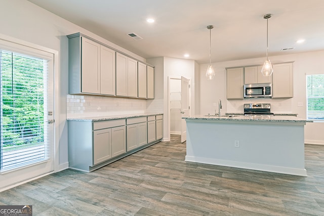 kitchen with wood-type flooring, stainless steel appliances, plenty of natural light, and gray cabinetry