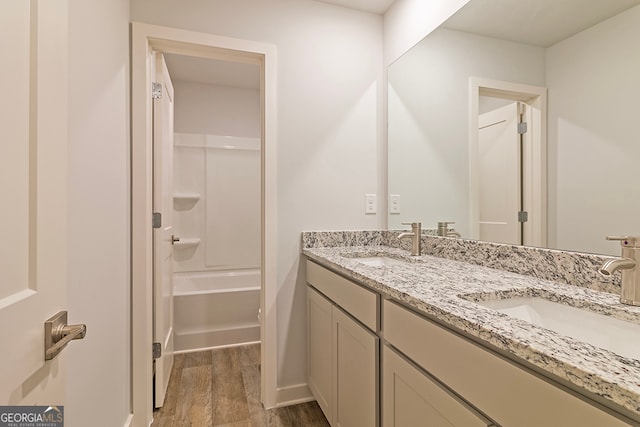 bathroom featuring wood-type flooring, washtub / shower combination, and vanity