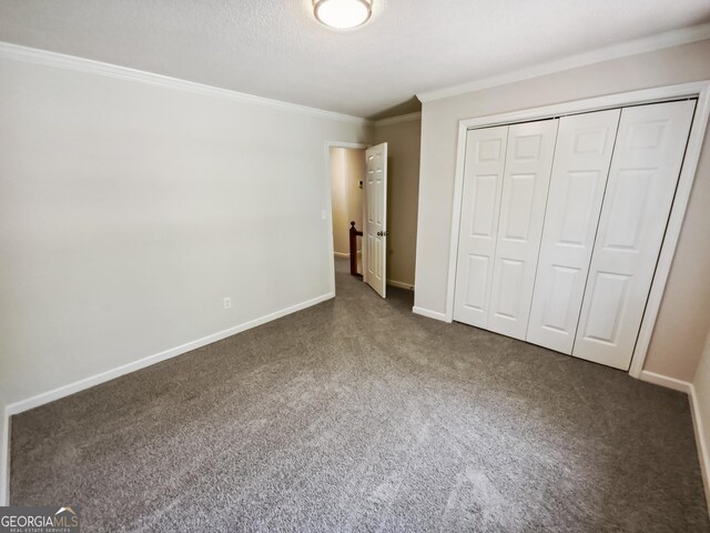 unfurnished bedroom featuring dark carpet, a closet, and crown molding