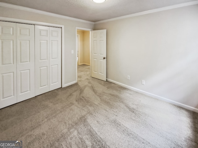 unfurnished bedroom featuring a textured ceiling, ornamental molding, light colored carpet, and a closet