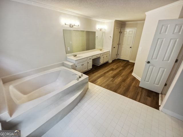 bathroom featuring a textured ceiling, a bathtub, hardwood / wood-style floors, ornamental molding, and vanity