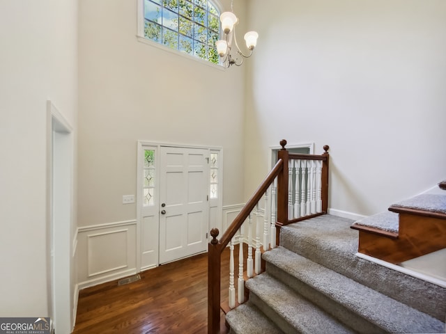 entrance foyer featuring an inviting chandelier, a towering ceiling, and dark hardwood / wood-style floors