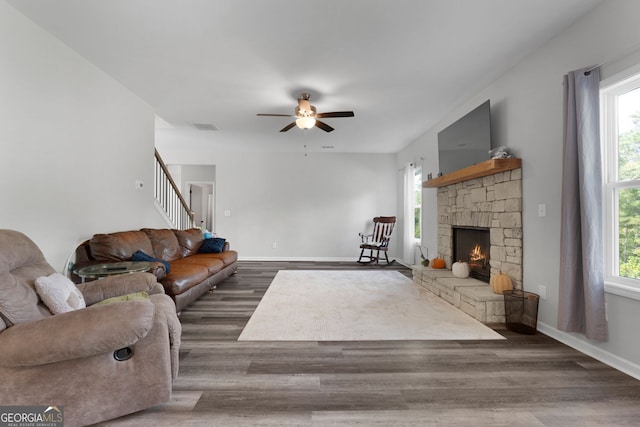 living room featuring ceiling fan, a fireplace, and dark hardwood / wood-style flooring