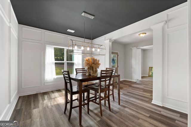 dining space with a chandelier, hardwood / wood-style floors, and ornate columns