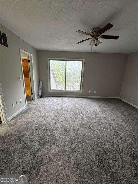 spare room featuring radiator heating unit, carpet, ceiling fan, and a textured ceiling