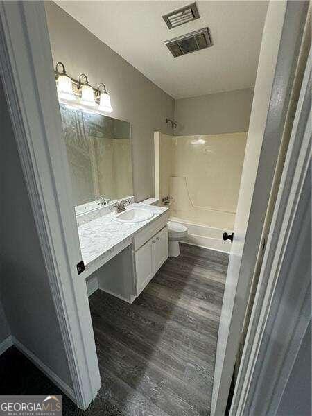 full bathroom featuring shower / tub combination, wood-type flooring, vanity, and toilet