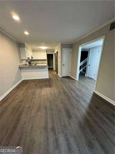 unfurnished living room featuring crown molding and dark hardwood / wood-style flooring