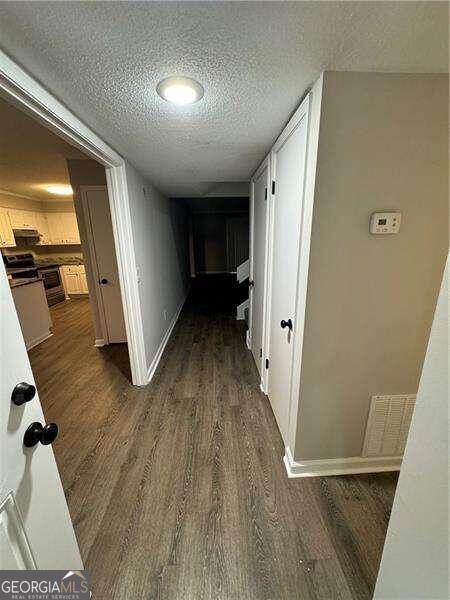 corridor featuring a textured ceiling and dark hardwood / wood-style floors