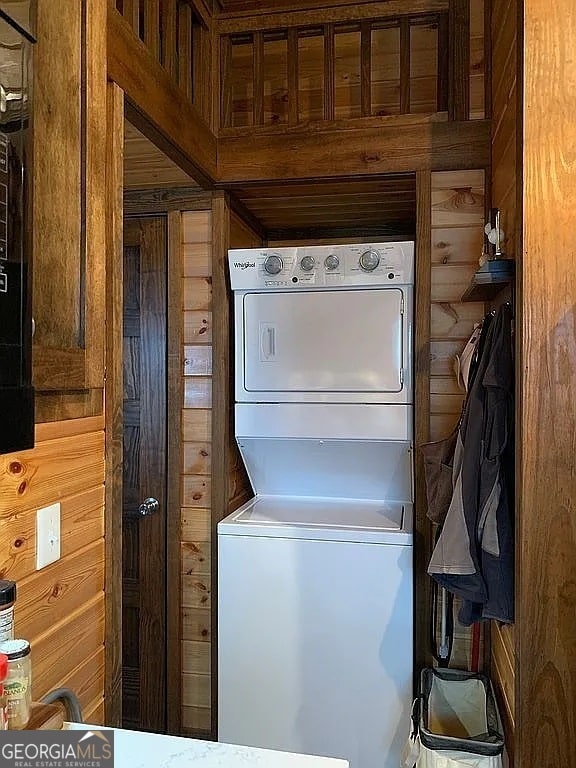 laundry room with stacked washing maching and dryer and wood walls