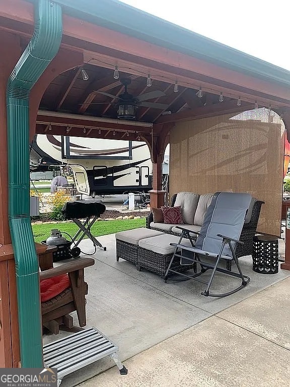 view of patio featuring ceiling fan, an outdoor living space, and a gazebo