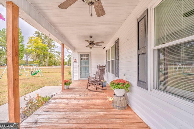 wooden deck with ceiling fan, a playground, covered porch, and a yard