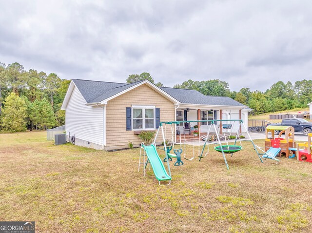 rear view of property with a playground, central air condition unit, and a yard