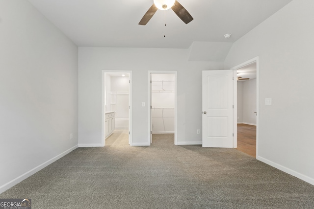 unfurnished bedroom with connected bathroom, ceiling fan, light colored carpet, a walk in closet, and a closet